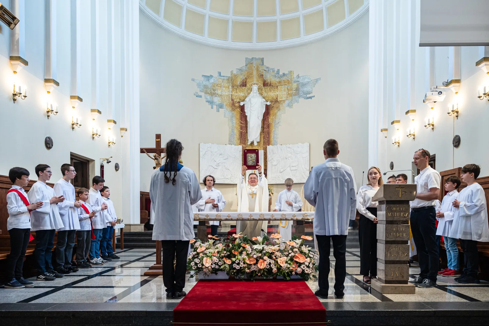Ksiądz unosi Ewangeliarz przy ołtarzu głównym